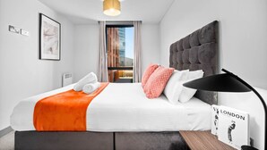 Habitación de hotel moderna con una cama grande, vista a la ciudad y un cuadro en la pared.