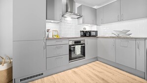 Una cocina moderna con armarios grises, horno empotrado y microondas en la encimera.