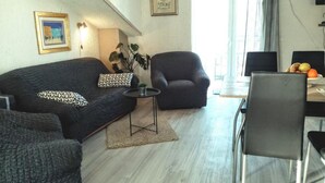 A modern living room with a dark grey sofa, a small round table, and a dark armchair. There is a plant on the table and a framed picture on the wall. - Apartments Silva - Superior Two Bedroom Apartment with Balcony and Sea View (Slatine)