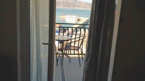 A balcony with a table and chairs, overlooking a coastal area with a ship and mountains in the distance. - Apartments Silva - Superior Two Bedroom Apartment with Balcony and Sea View (Slatine)