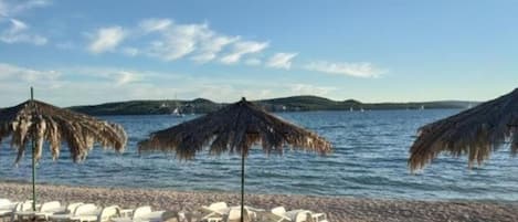 Relax in a casual beachside seating area with lounge chairs and thatched umbrellas.