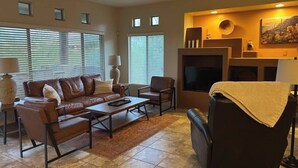 A living room with a brown leather sofa, a coffee table, and a fireplace. - Welcome to Resort Casita (Oro Valley)