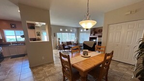 A spacious dining area with a wooden table and chairs, a hanging light fixture, and a view into the kitchen area. - Welcome to Resort Casita (Oro Valley)