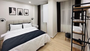 A modern hotel room with a bed, a bedside table, a lamp, a bunk bed, and a wardrobe. - Two-Bedroom Apartment in Taksim - No: 9 (İstanbul)