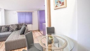 A modern living room with a grey sofa, a glass coffee table, and a painting on the wall.