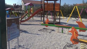 Ein Spielplatz mit Rutsche, Schaukeln und einer Kletterkonstruktion.