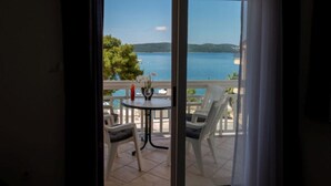 A balcony with a table and chairs, overlooking a body of water and greenery.