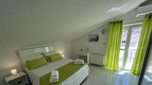 A modern bedroom with a bed, bedside tables, a radiator, and a view through a glass door. - Apartments Tomi - Double Room With Sea View (3) (Trogir)