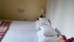 A hotel room with a bed, a bedside table with a lamp, and a wall-mounted light fixture.
