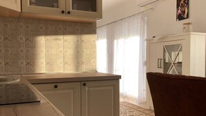 A kitchen with a wooden countertop, white cabinets, and patterned backsplash. - Apartment Bordoa de Macura with Bay View (Zadar)