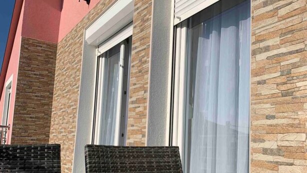 A building with stone facade, large windows, and outdoor seating. - Apartment Bordoa de Macura with Bay View (Zadar)