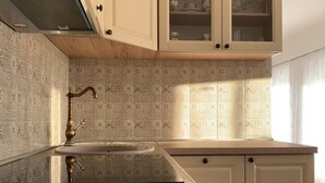 A kitchen with patterned tiles, a sink, and wooden cabinets. - Apartment Bordoa de Macura with Bay View (Zadar)