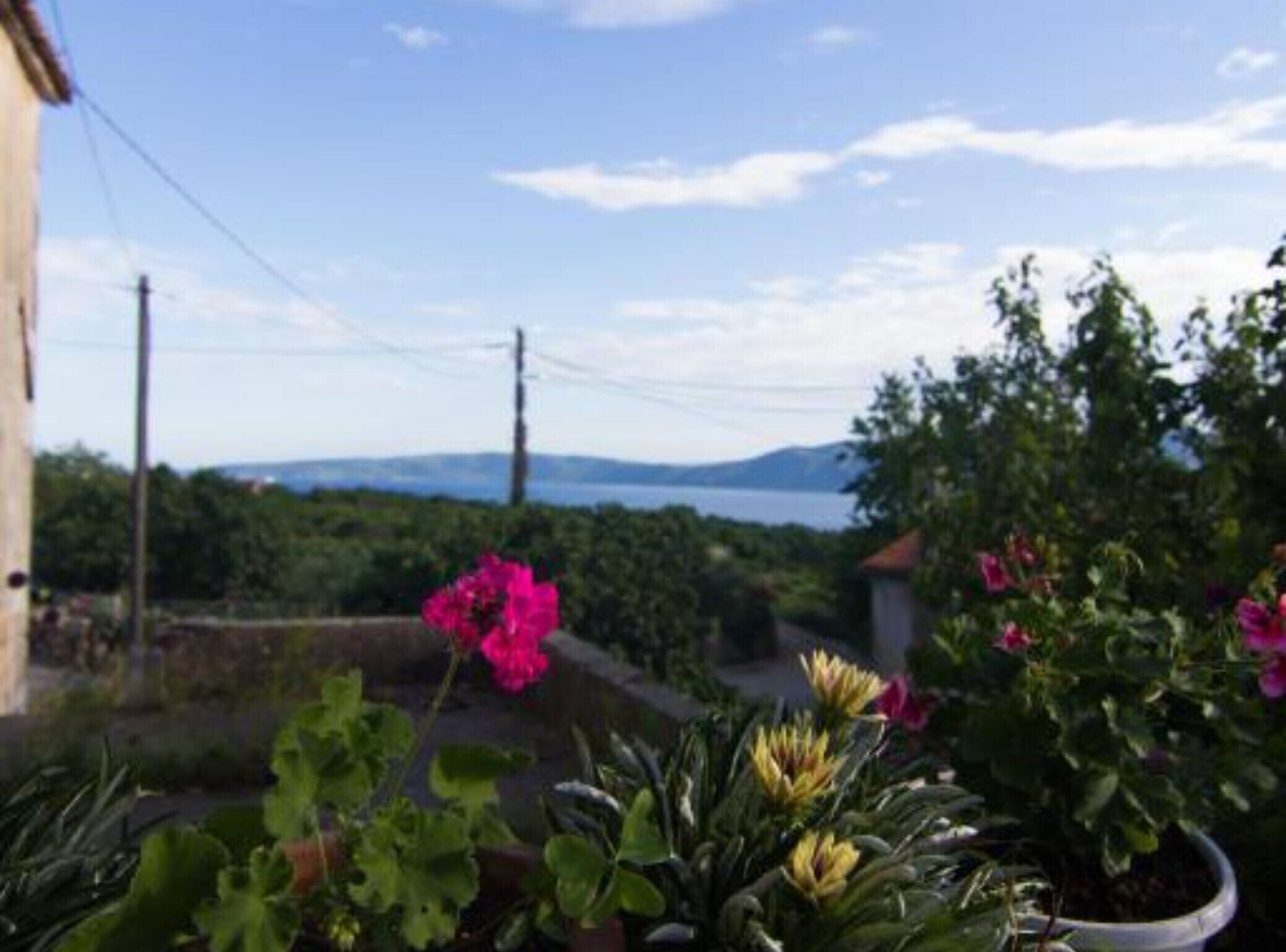 A view of a coastal landscape with a clear sky, a body of water, and distant mountains.