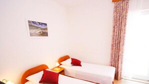 Une chambre avec deux lits, une table de chevet, une lampe et une fenêtre avec des rideaux.