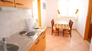 Una cocina compacta con estufa, lavamanos y una mesa de comedor con sillas.