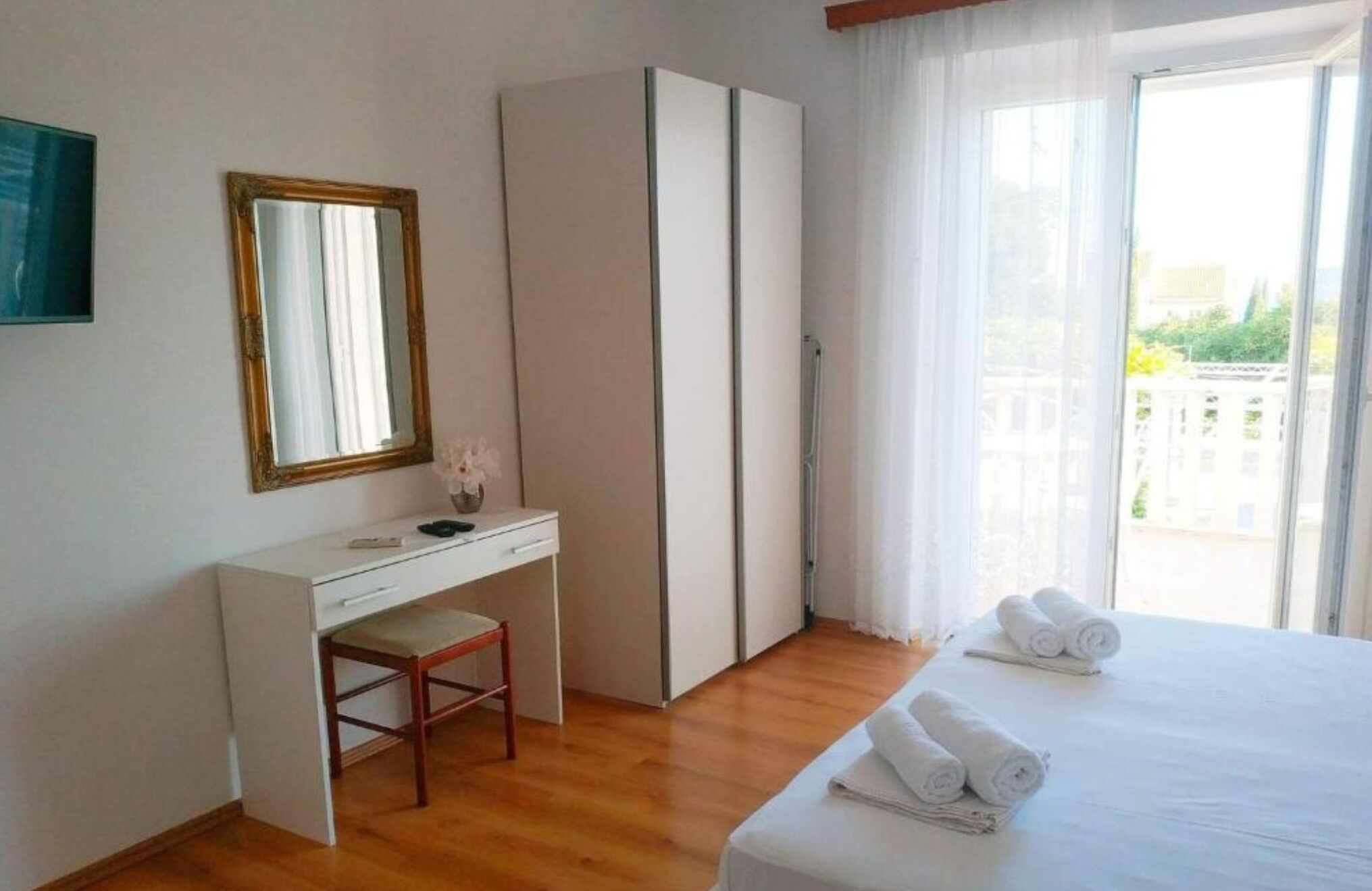 A hotel room with a bed, a desk, a chair, a wardrobe, and a large window with a view.