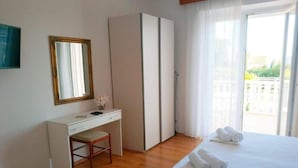 A hotel room with a bed, a desk, a chair, a wardrobe, and a large window with a view. - Double Or Twin Room With Terrace and Sea View 10 (Mlini)