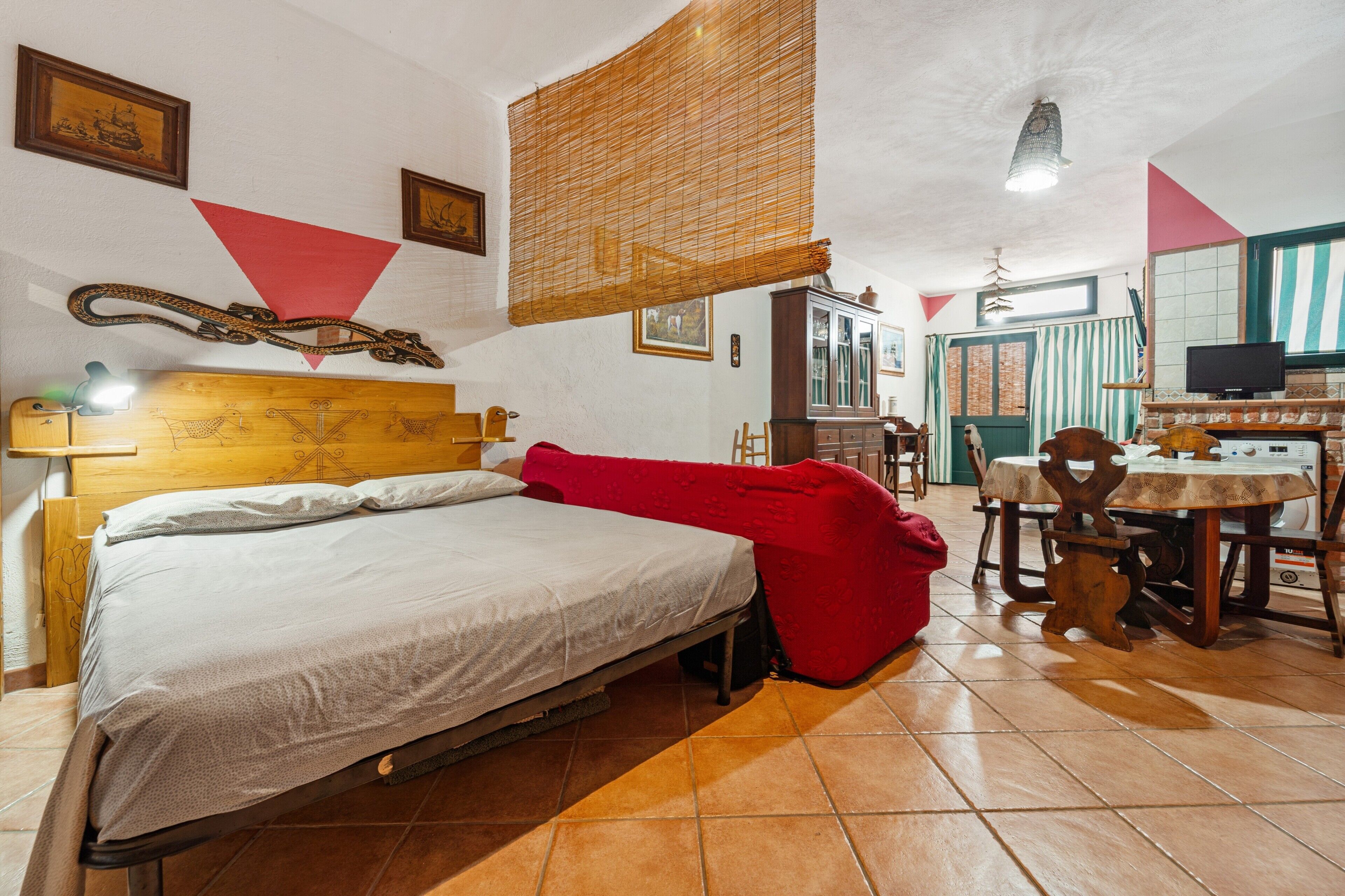 A room with a bed, a dining table with chairs, a television, and a cabinet.