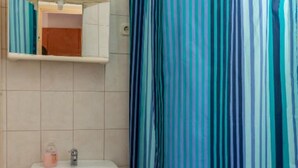 Un baño con un lavabo blanco, un espejo encima y una cortina de ducha a rayas.