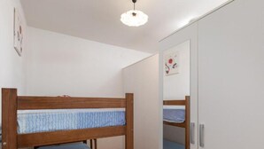 Un dormitorio con una litera, un armario y un espejo.