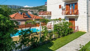 Un bâtiment blanc doté de balcons, d’une piscine et offrant une vue sur une ville et des montagnes.