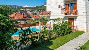Un bâtiment blanc doté de balcons, d’une piscine et offrant une vue sur une ville et des montagnes.