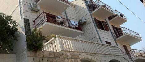A multi-story building with balconies, air conditioning units, and a stone facade.