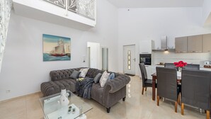 A modern living room with a grey sofa, a glass coffee table, and a dining area with a white table and chairs. - Villa Shaula 2 - Three Bedroom House with Pool (Šibenik)