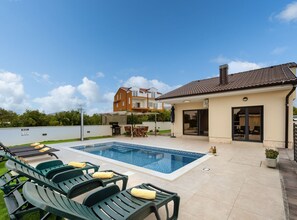 A swimming pool with lounge chairs and a covered patio area.