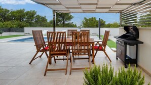 An outdoor patio with a table and chairs, a grill, and a view of a swimming pool. - Villa Shaula 1 - Three Bedroom House with Pool (Šibenik)