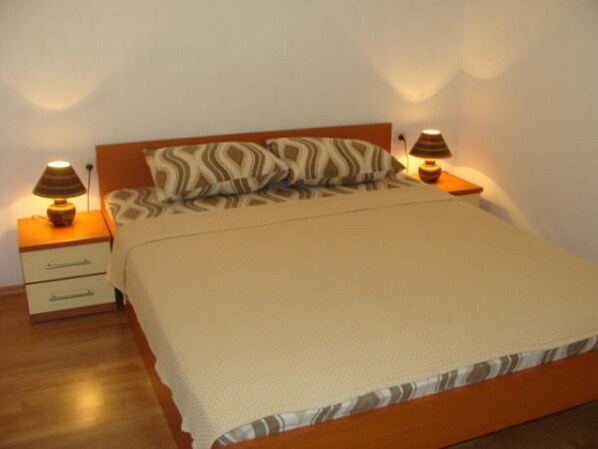 A bedroom with a bed, two bedside tables, a nightstand, and a lamp.