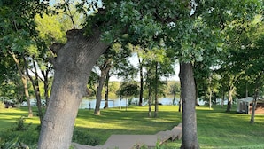 A park with a paved walkway, trees, and a lake in the background.