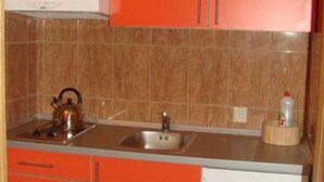 A kitchen with orange cabinets, a stainless steel kettle, and a sink. - Apartments Višnja - Classic One Bedroom Apartment (Klek)