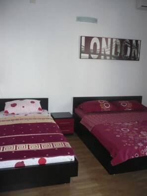 A bedroom with two beds, a wall-mounted artwork with the word "LONDON," and a small nightstand between the beds. - Apartments Višnja - Standard One Bedroom Apartment (Klek)