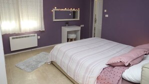 Un dormitorio con cama, tocador con espejo y radiador.