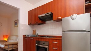 A compact kitchen with wooden cabinets, a stainless steel refrigerator, and a built-in oven.