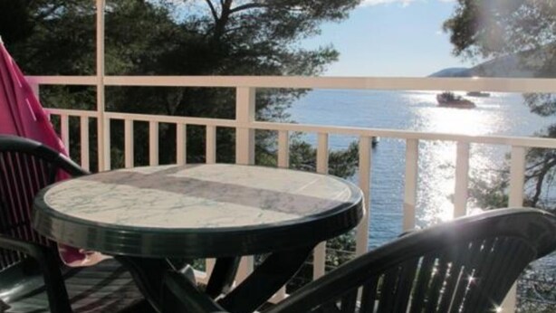 A balcony with a table and chairs overlooking a body of water and trees. - Seafront Charming Apartments Kosirina One Bedroom (Brna)