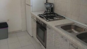 A compact kitchen with a gas stove, a built-in oven, a sink, and a refrigerator. - Seafront Charming Apartments Kosirina One Bedroom (Brna)