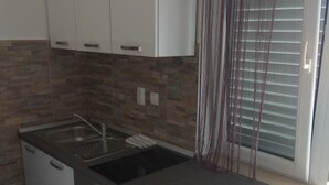 A kitchen with a granite countertop, a stainless steel sink, and white cabinetry. - Seafront Charming Apartments Kosirina Studio 4 (Brna)