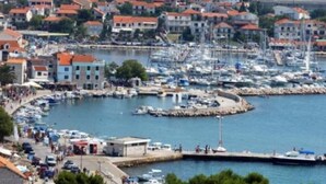 Eine Küstenstadt mit einem Hafen voller Boote, umgeben von Gebäuden mit roten Ziegeldächern.