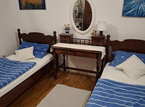 Une chambre avec deux lits, une commode, un miroir et une petite table.
