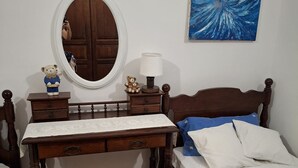 A bedroom with a wooden bed, a bedside table with a lamp, a mirror, and a small dresser. - Apartment Jadranka - Two Bedroom Apartment With Balcony And Sea View (Korcula)