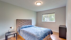 Ein Schlafzimmer mit einem Bett, einem Nachttisch mit Lampe, einem Fenster und einem eingebauten Lautsprecher.