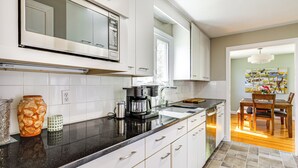Une cuisine moderne avec des meubles blancs, un plan de travail noir et une machine à café.