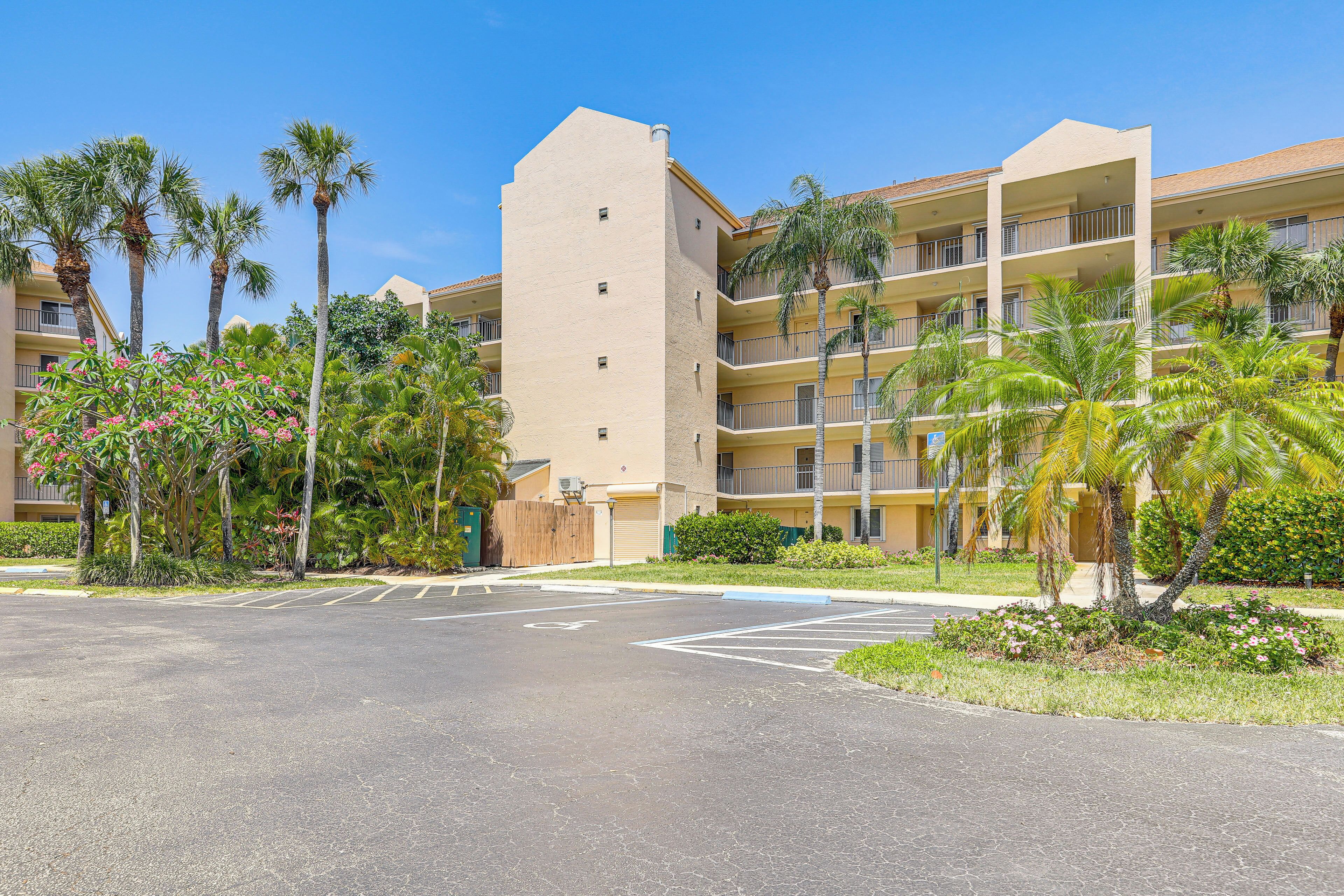 A multi-story hotel with a central courtyard, palm trees, and a parking lot.