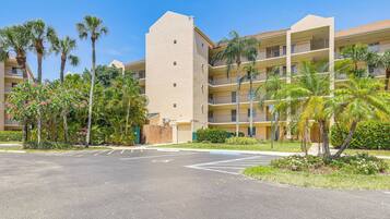 A multi-story hotel with a central courtyard, palm trees, and a parking lot.