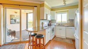 A kitchen with white cabinets, a microwave, a refrigerator, and a dining area with two stools. - 1/2 Mi to Jupiter Beach: Penthouse Condo w/ Views (Jupiter)