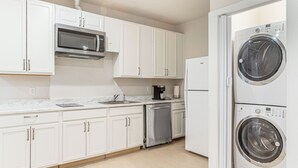 A modern kitchen with white cabinets, a stainless steel microwave, a coffee maker, and a double-door washing machine. - 12 Mi to Hospitals: Modern Apartment in Aurora! (Aurora)