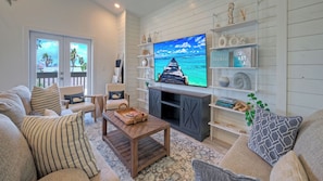 Una sala de estar con televisión, estanterías de madera y vista al océano.