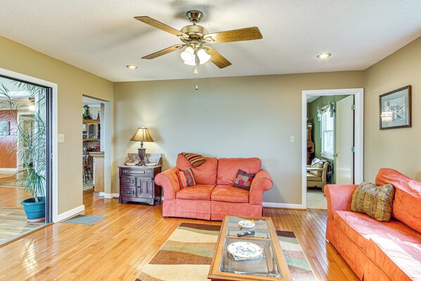 A living room with a ceiling fan, a sofa, a coffee table, and a rug.